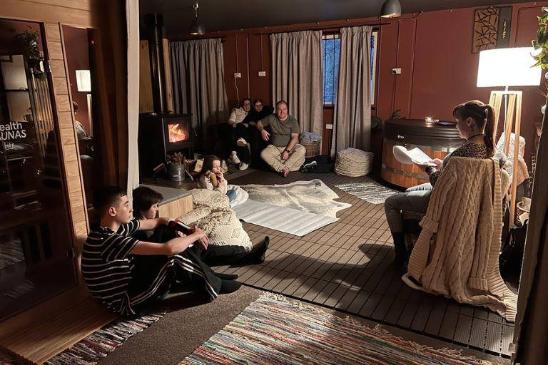 A peaceful lounge area at Eltham Wellness Centre featuring an infrared sauna, cozy seating, soft rugs, and warm lighting. Individuals are seen resting and stretching, creating a space for relaxation and recovery.